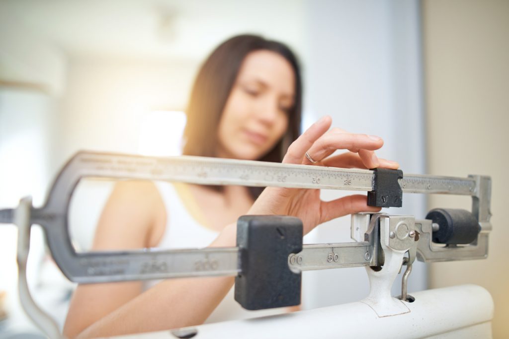 Young woman measuring weight loss due to Detox diet